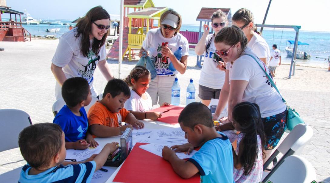 Volunteers and kids making posters for a community event in San Pedro, Belize. Projects Abroad volunteers managing kids at a Youth Development Project in Belize.